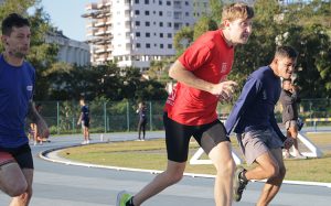 Três jovens adultos correndo na pista de atletismo da UFSC